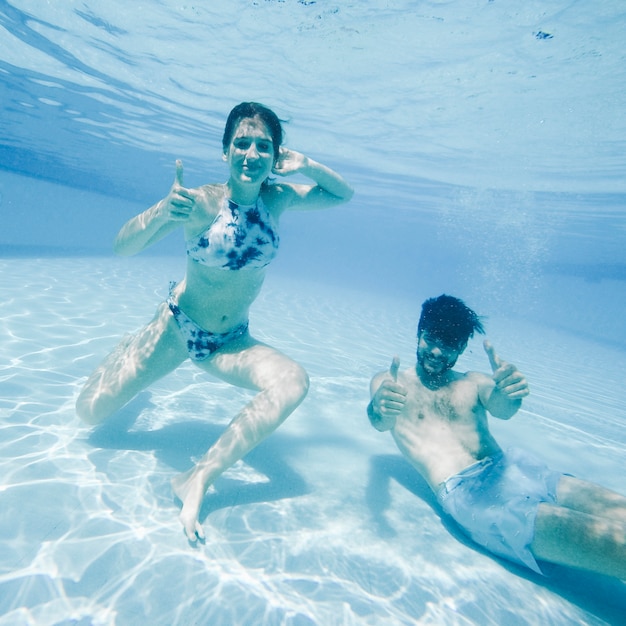 Pareja joven buceando en piscina