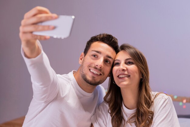 Pareja joven en la cama tomando selfie