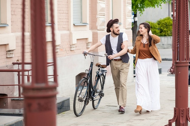 Pareja joven caminando con bicicleta y abrazos