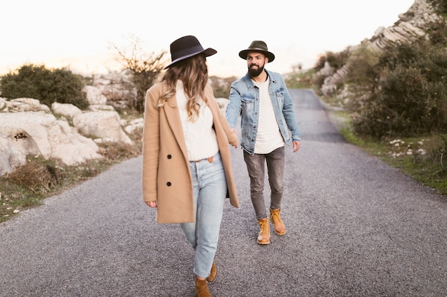 Foto gratuita pareja joven caminando por la carretera de montaña