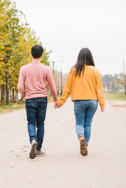 Pareja joven caminando por la carretera