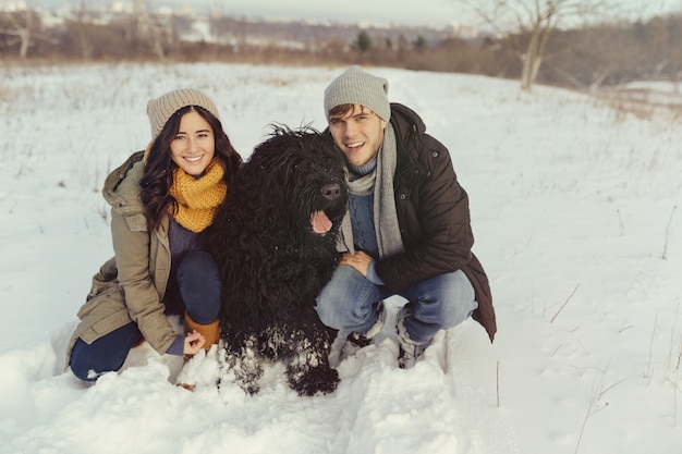 Pareja joven caminando con un perro en un día de invierno