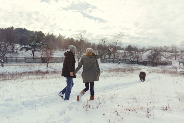 Foto gratuita pareja joven caminando con un perro en un día de invierno