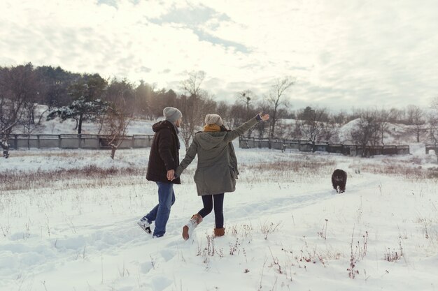 Pareja joven caminando con un perro en un día de invierno
