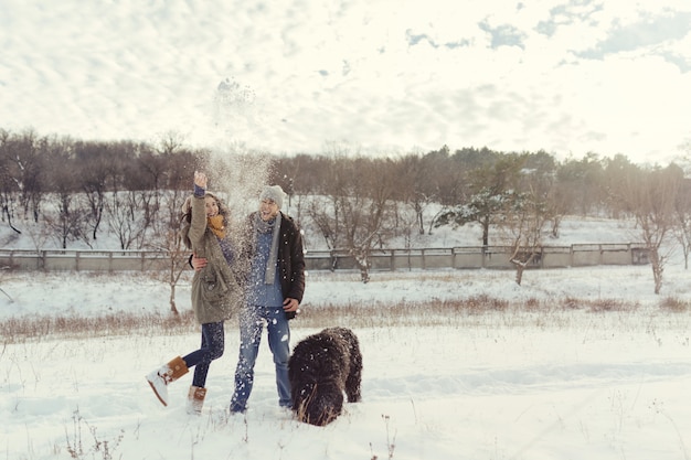 Pareja joven caminando con un perro en un día de invierno