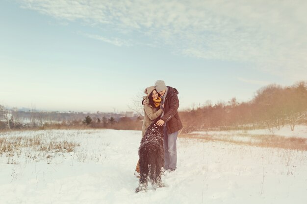 Pareja joven caminando con un perro en un día de invierno