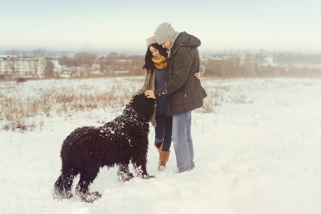 Pareja joven caminando con un perro en un día de invierno