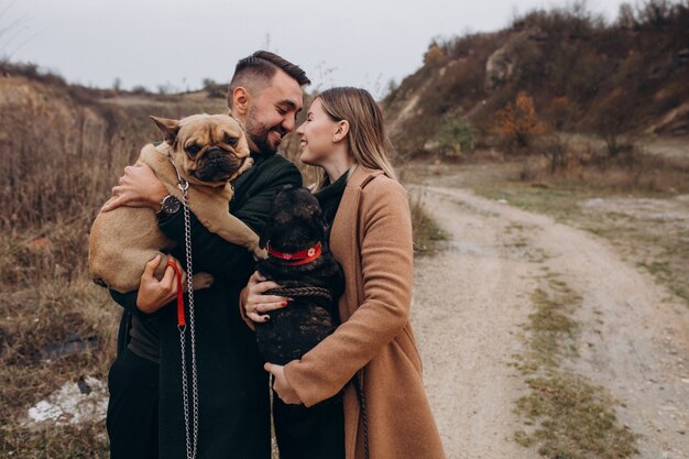 Pareja joven caminando sus bulldogs franceses en el parque