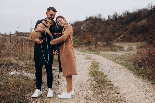 Pareja joven caminando sus bulldogs franceses en el parque