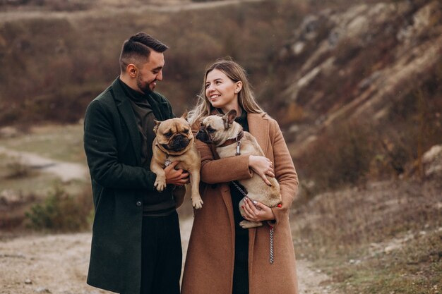 Pareja joven caminando sus bulldogs franceses en el parque