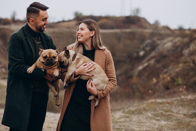 Pareja joven caminando sus bulldogs franceses en el parque