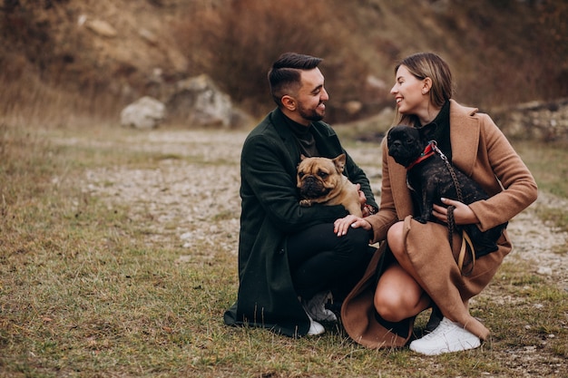 Pareja joven caminando sus bulldogs franceses en el parque