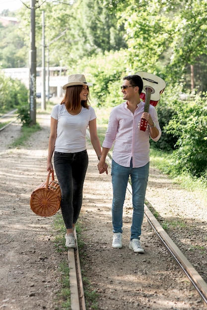 Pareja joven caminando en una vía férrea