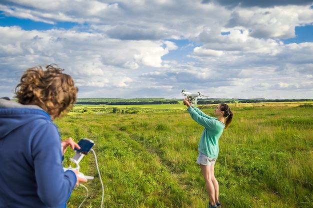 Pareja joven en un campo lanza el dron al cielo