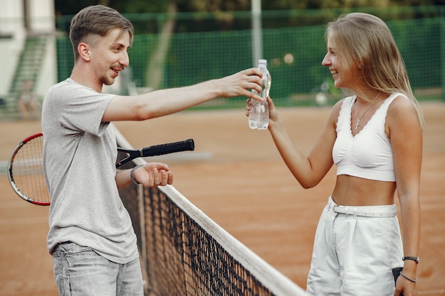 Pareja joven en la cancha de tenis. Dos tenistas se toman un descanso.