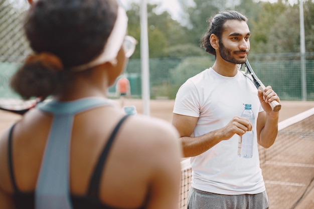 Foto gratuita pareja joven, en, un, cancha de tenis