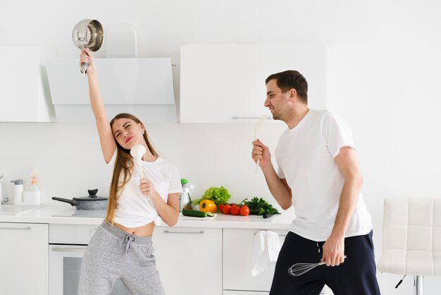 Pareja joven cantando mientras cocina