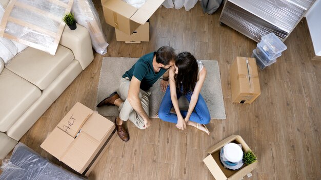 Pareja joven en casa nueva y desembalaje de cajas de cartón. Casi terminado de mudarse.