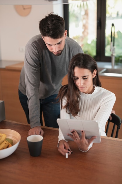 Pareja joven en casa usando tableta