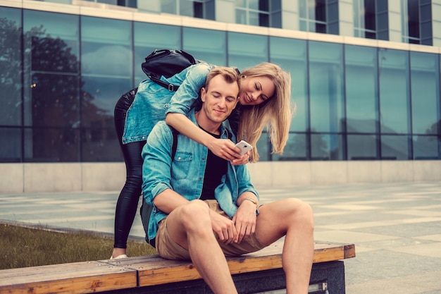 Pareja joven casual con smartphone en una ciudad.