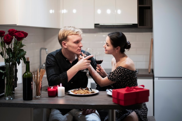 Pareja joven celebrando el día de san valentín mientras almuerza y vino juntos