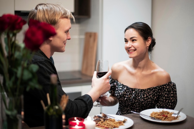 Pareja joven celebrando el día de san valentín mientras almuerza y vino juntos