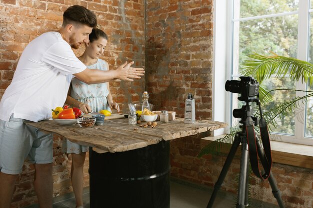 Pareja joven cocinando y grabando video en vivo para vlog y redes sociales