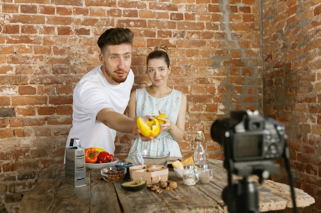 Pareja joven cocinando y grabando video en vivo para vlog y redes sociales