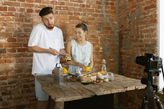 Pareja joven cocinando y grabando video en vivo para vlog y redes sociales