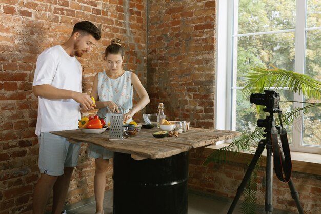 Pareja joven cocinando y grabando video en vivo para vlog y redes sociales