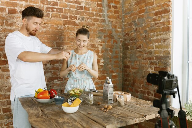 Pareja joven cocinando y grabando video en vivo para vlog y redes sociales