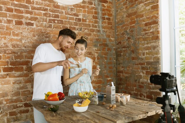 Pareja joven cocinando y grabando video en vivo para vlog y redes sociales