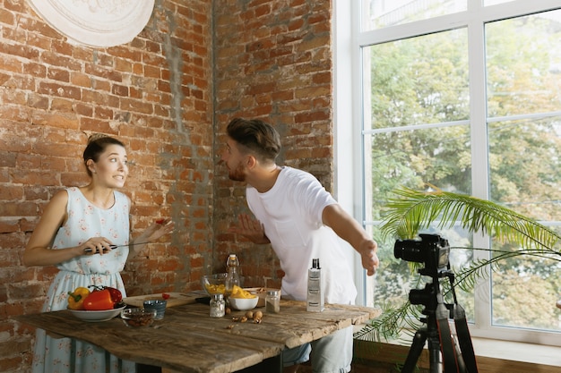 Pareja joven cocinando y grabando video en vivo para vlog y redes sociales