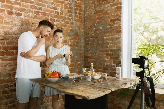 Pareja joven cocinando y grabando video en vivo para vlog y redes sociales