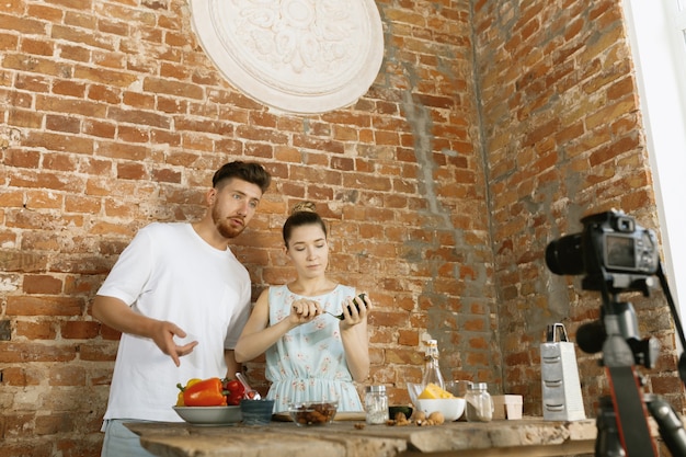 Foto gratuita pareja joven cocinando y grabando video en vivo para vlog y redes sociales