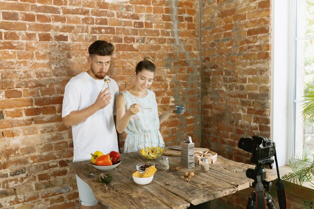 Pareja joven cocinando y grabando video en vivo para vlog y redes sociales