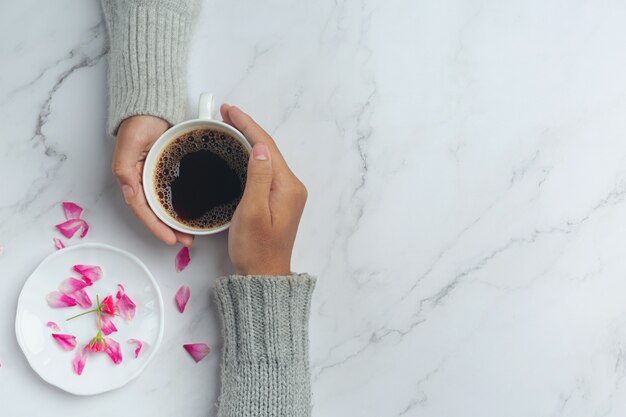 Pareja joven cogidos de la mano para comer café en una mesa de madera.