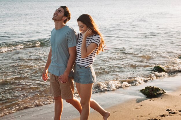 Pareja joven cogiéndose las manos en la playa