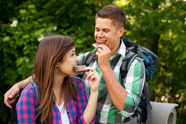 Pareja joven comiendo chocolate en el bosque