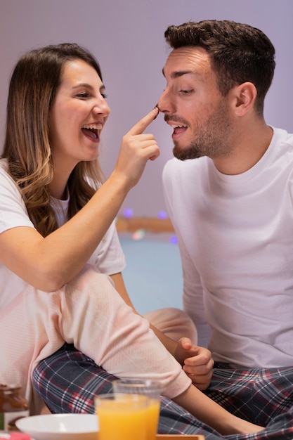 Pareja joven comiendo dulces en la cama