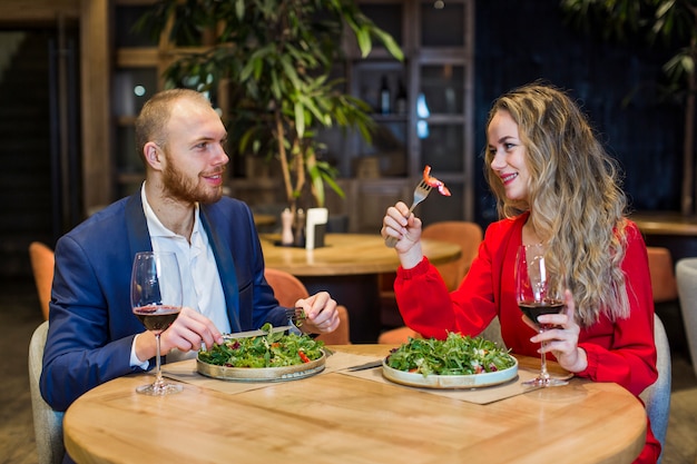 Pareja joven comiendo ensalada en el restaurante