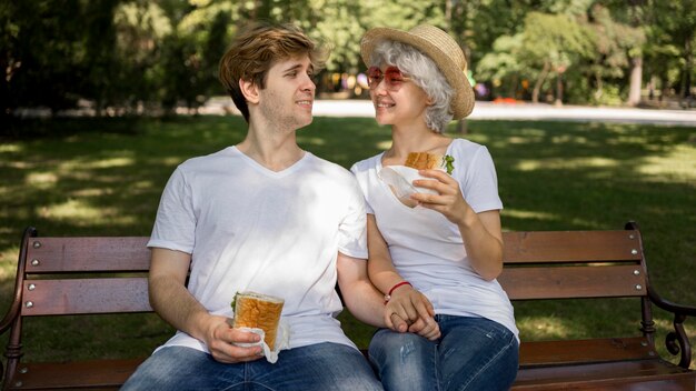 Pareja joven comiendo hamburguesas en el parque