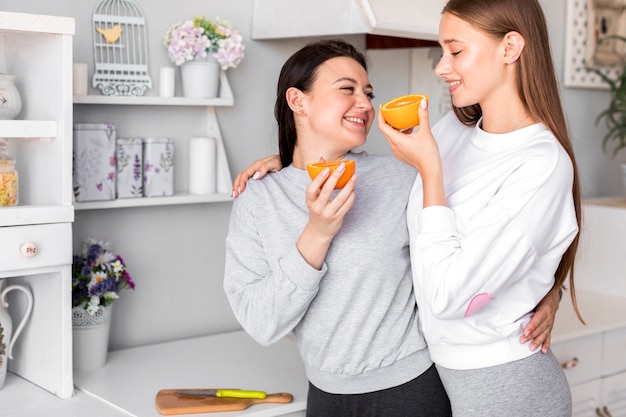 Pareja joven comiendo una naranja en la cocina