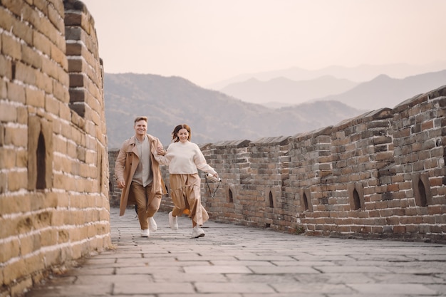 Pareja joven corriendo y girando en la Gran Muralla China