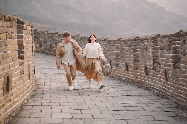 Pareja joven corriendo y girando en la Gran Muralla China