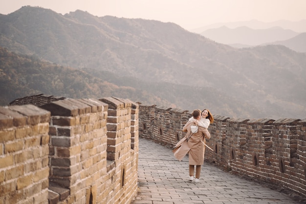 Pareja joven corriendo y girando en la Gran Muralla China