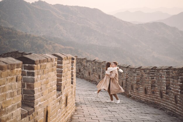 Pareja joven corriendo y girando en la Gran Muralla China