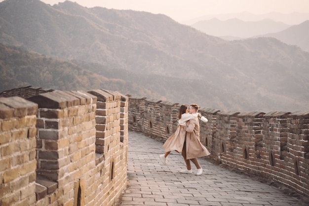 Pareja joven corriendo y girando en la Gran Muralla China