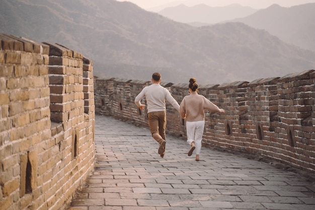 Pareja joven corriendo y girando en la gran muralla china