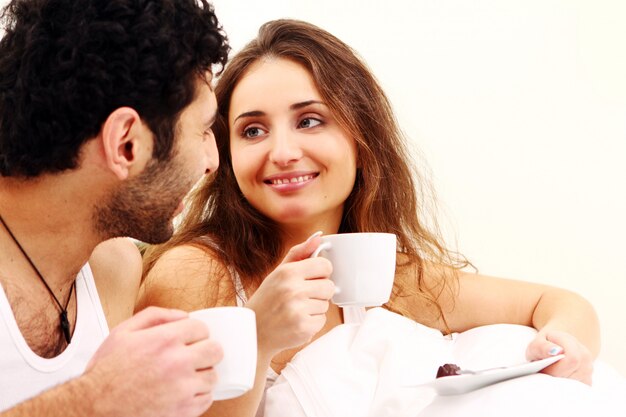 Pareja joven desayunando en la cama